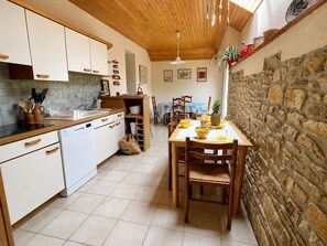 A kitchen with white cabinets, a wooden countertop, and a stone wall.