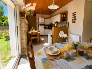 A cozy kitchen with wooden cabinets, a dining table set for breakfast, and a view of the garden.