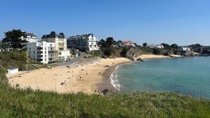 A coastal town with a sandy beach, buildings along the shore, and a clear blue sky. - TY AR STIVELL, the balance between land and sea 4-7PERS, MOELAN / SEA, WIFI, BEACHES (Moëlan-sur-Mer)