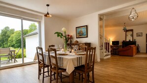 A dining area with a table set for six, wooden chairs, a vase with flowers, and a painting on the wall. - TY AR STIVELL, the balance between land and sea 4-7PERS, MOELAN / SEA, WIFI, BEACHES (Moëlan-sur-Mer)