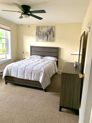 Cozy bedroom with a single bed, ceiling fan, and dresser, offering a comfortable retreat.