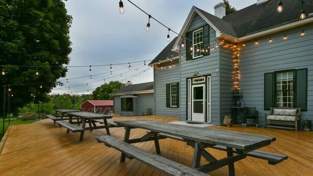 A wooden deck with picnic tables and string lights.