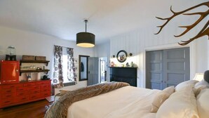 A bedroom with a large bed, a red dresser, a fireplace, and a ceiling light fixture.