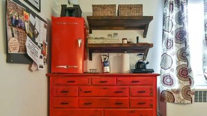 A red dresser with multiple drawers, a small refrigerator, and a shelf above it.