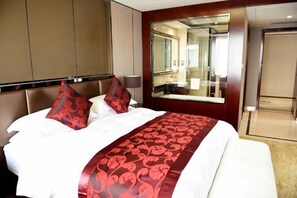 Una habitación de hotel con una cama grande, un espejo y una puerta que da a un baño.