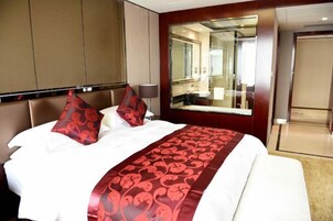 Una habitación de hotel con una cama grande, un espejo y una puerta que da a un baño.