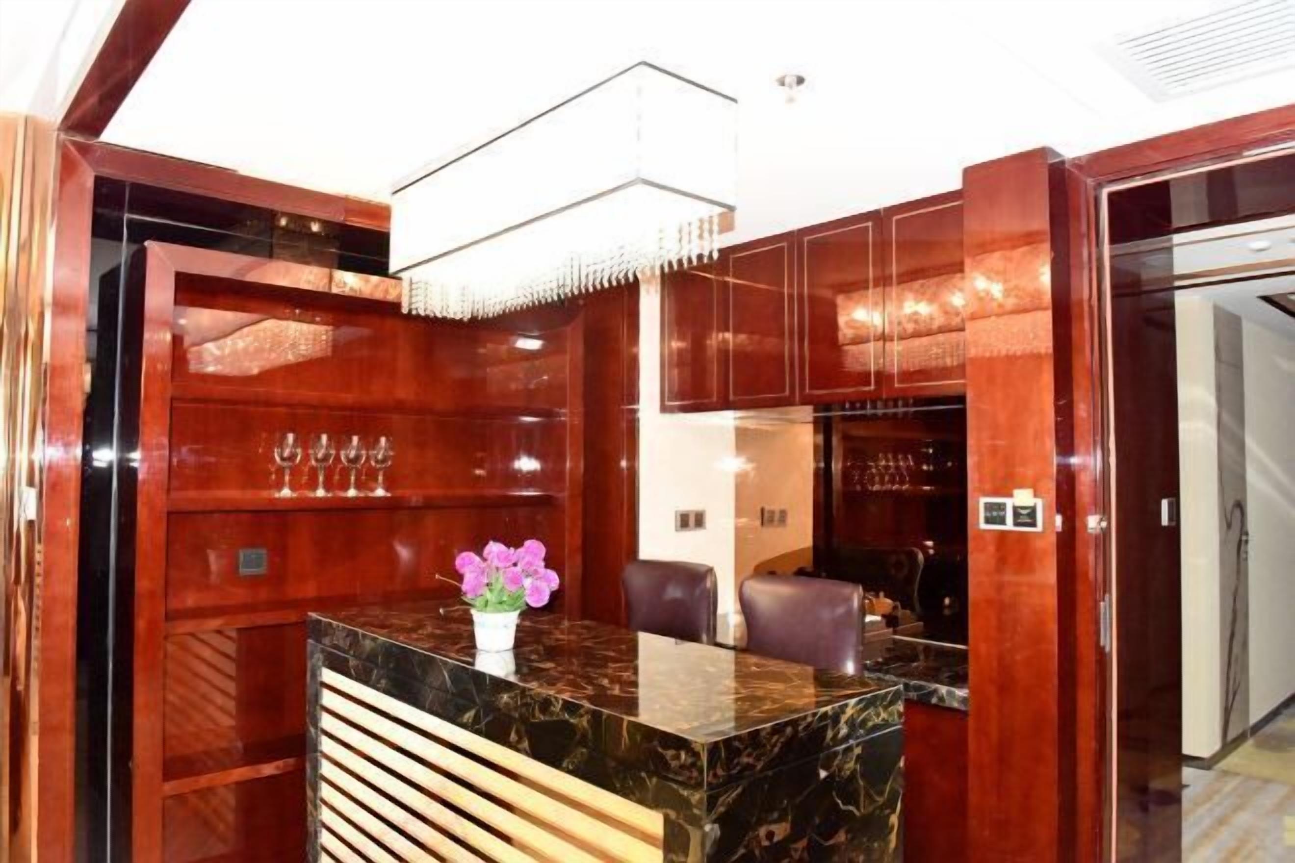Un mostrador de recepción con encimera de mármol, listones de madera y un jarrón de flores.