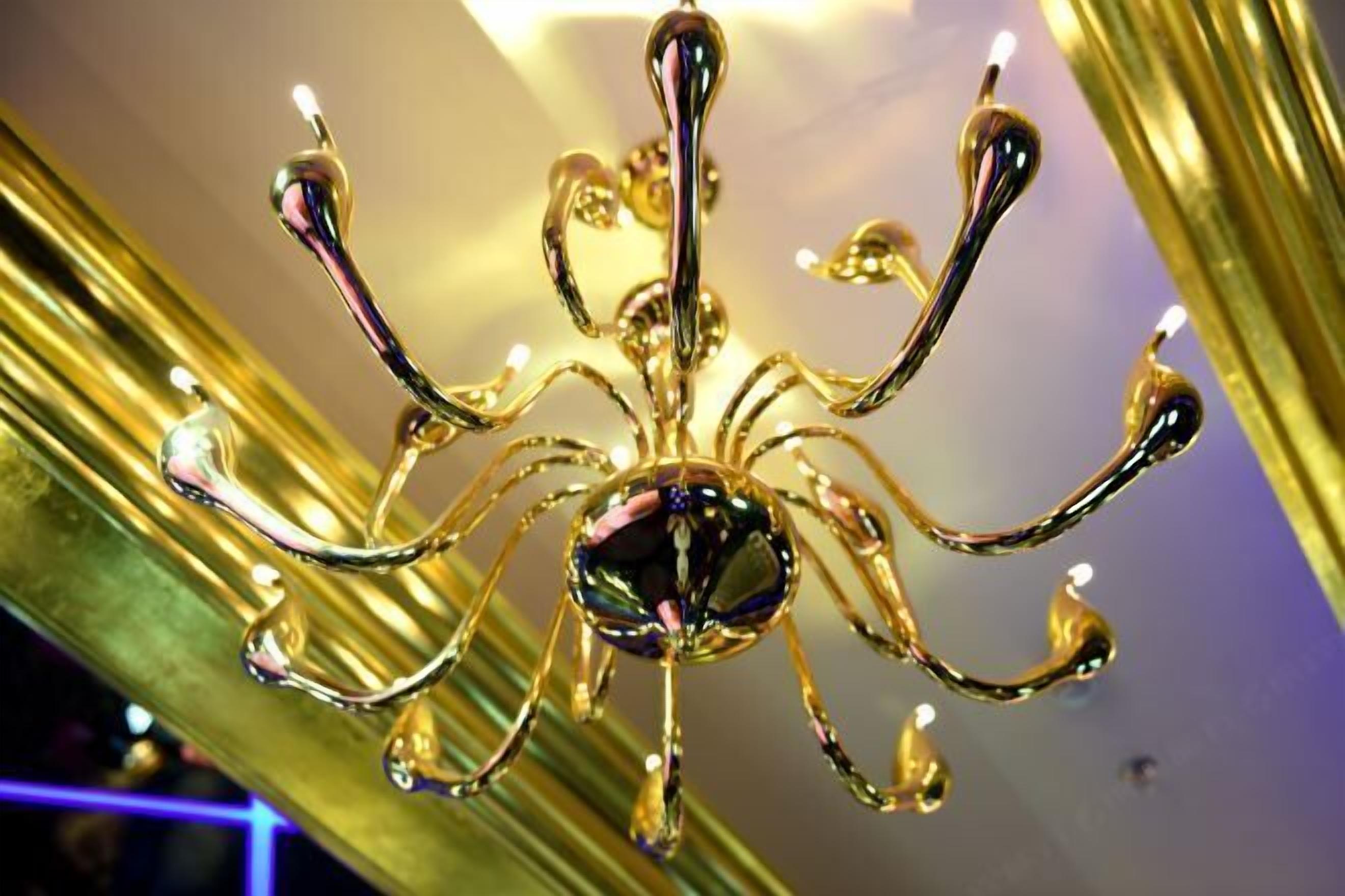 Un lustre à plusieurs bras et orné d’un cristal central.