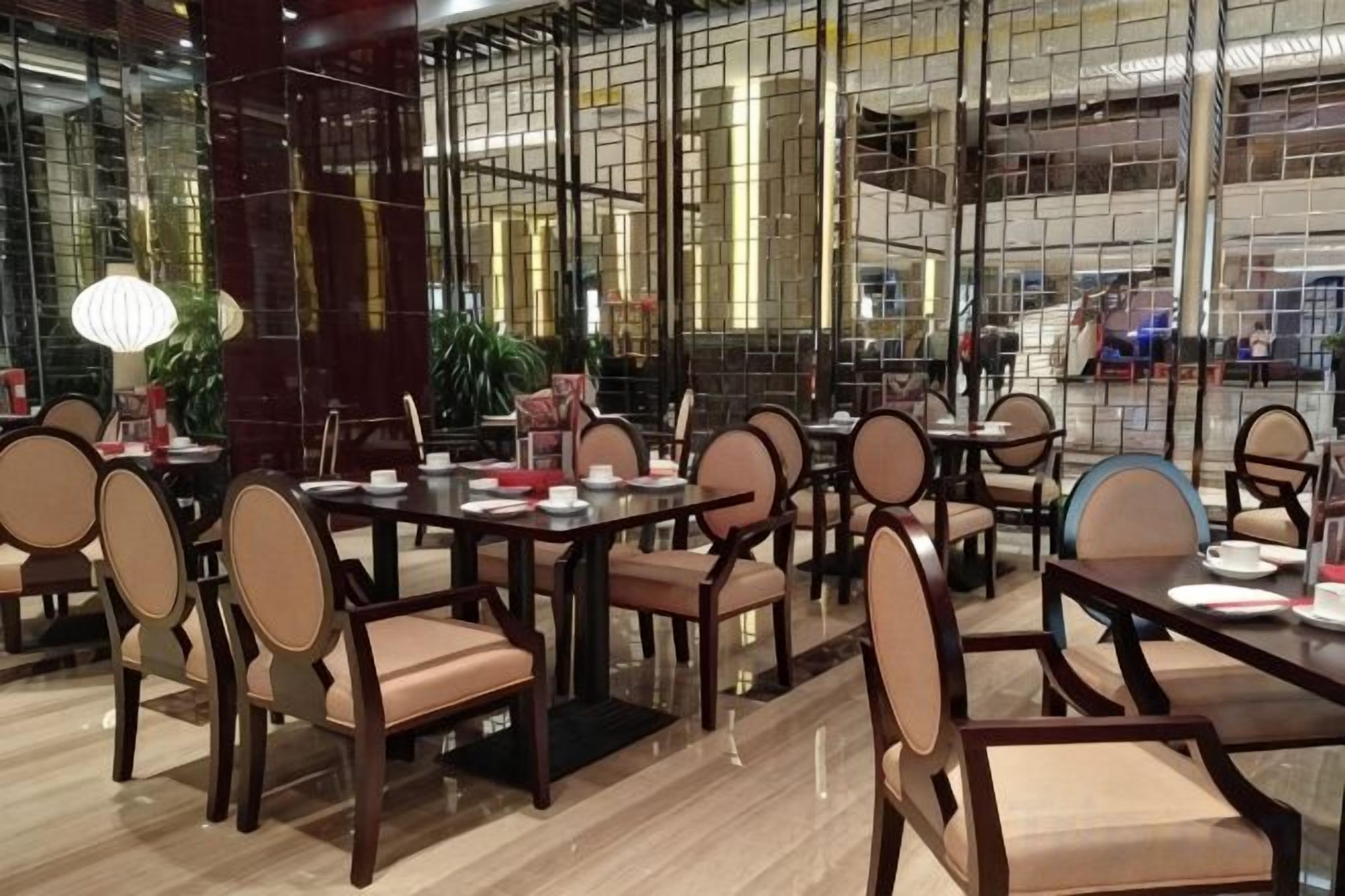 A restaurant with multiple tables and chairs, a polished floor, and large windows.