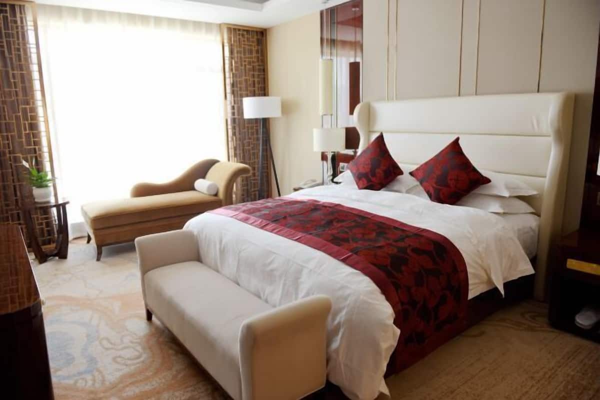 A hotel room with a large bed, a sofa, a desk, and a lamp.
