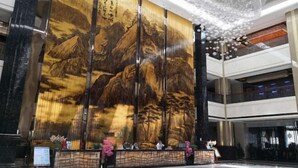 A lobby with a large wall mural, a reception desk, and a modern chandelier. - Hongquan Hotel (Pingliang)