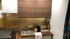 A compact kitchen with a sink, a coffee machine, and a microwave. - Apartment 19 rue Gutenberg (Paris)