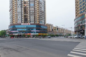 Un edificio de varios pisos con locales comerciales en la planta baja, un paso de peatones y vehículos en la calle.