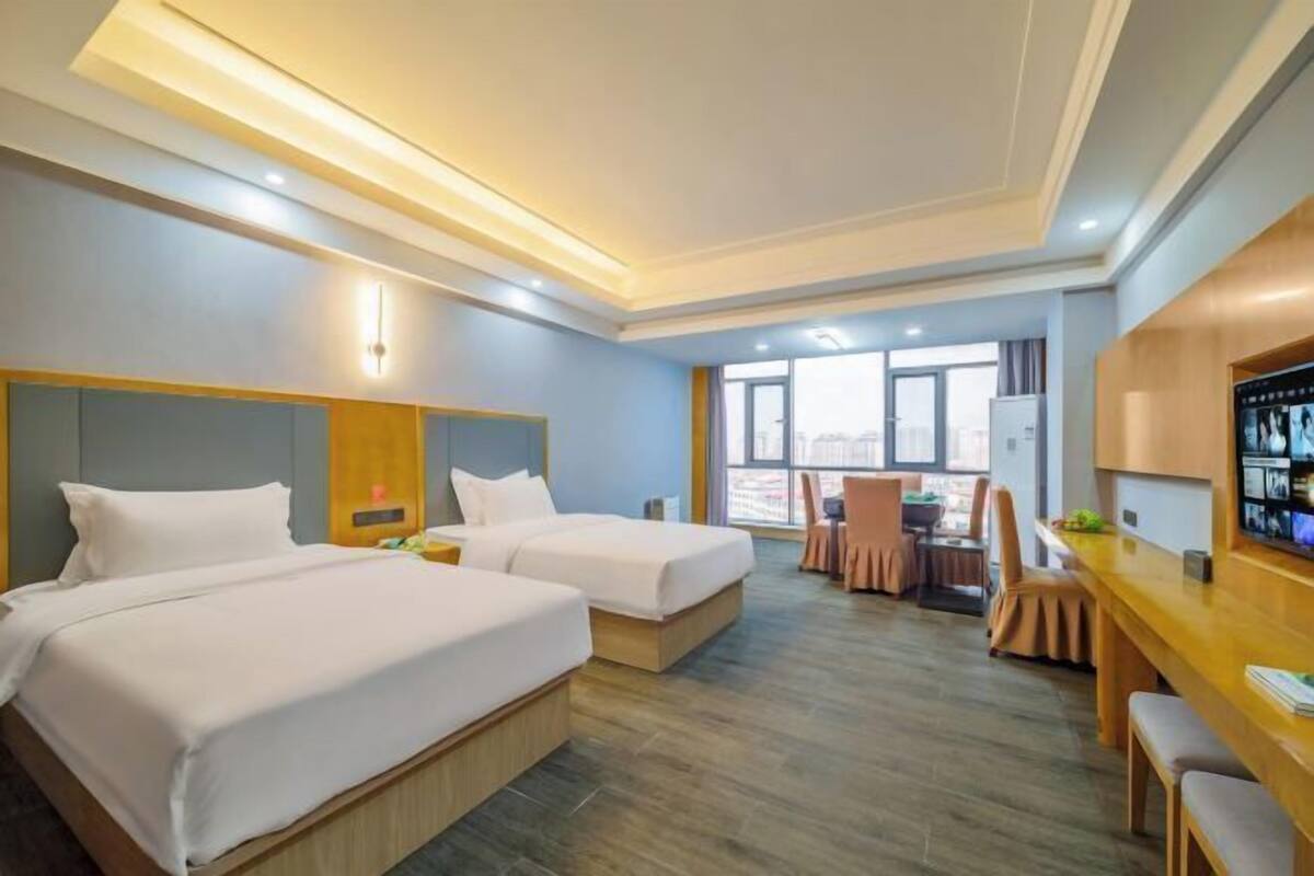 Een hotelkamer met twee bedden, een bureau, een stoel en een televisie.