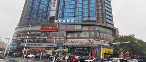 A multi-story building with a large number of windows, a pedestrian crossing, and various vehicles on the street.