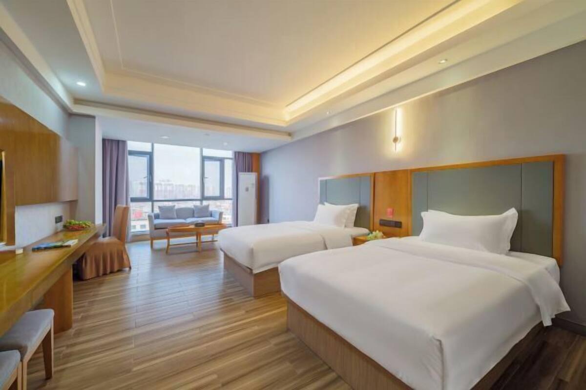 Hotelkamer met twee bedden, een bureau en een zithoek met uitzicht over de stad.
