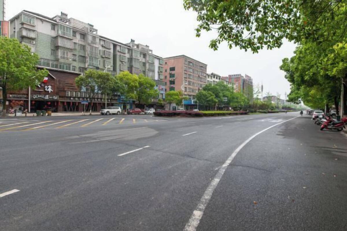 Een meerlaags gebouw met een commerciële begane grond, een zebrapad en geparkeerde motorfietsen.