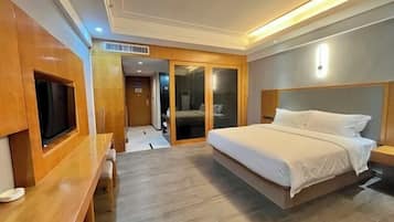 A modern hotel room with a large bed, a wooden desk, and a sliding door closet.