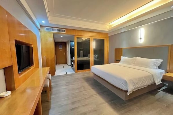 A modern hotel room with a large bed, a wooden desk, and a sliding door closet. - Dongting Hotel (Nan County)