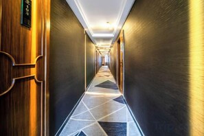 A hotel corridor with a geometric patterned floor, wooden doors, and a modern ceiling design. - Haoshuimian Hotel (Zhenjiang)