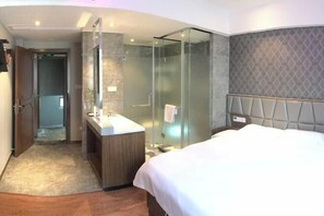 A modern hotel room with a large bed, a glass-enclosed shower, a vanity with a mirror, and a patterned wall. - Haoshuimian Hotel (Zhenjiang)