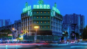 Un hotel con fachada verde y señalización iluminada.