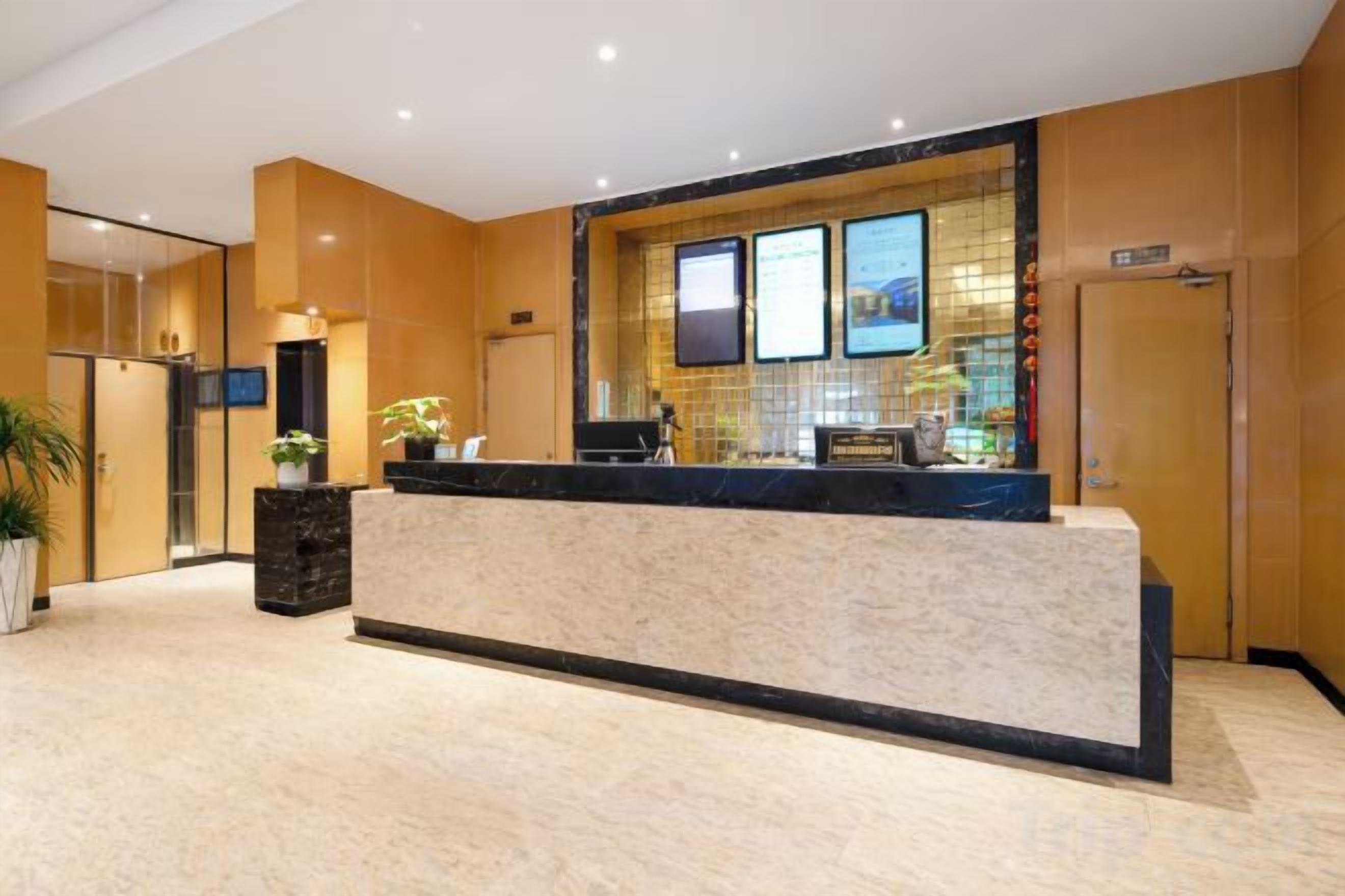 A hotel reception area with a marble counter, a reception desk, a large window, and a potted plant.