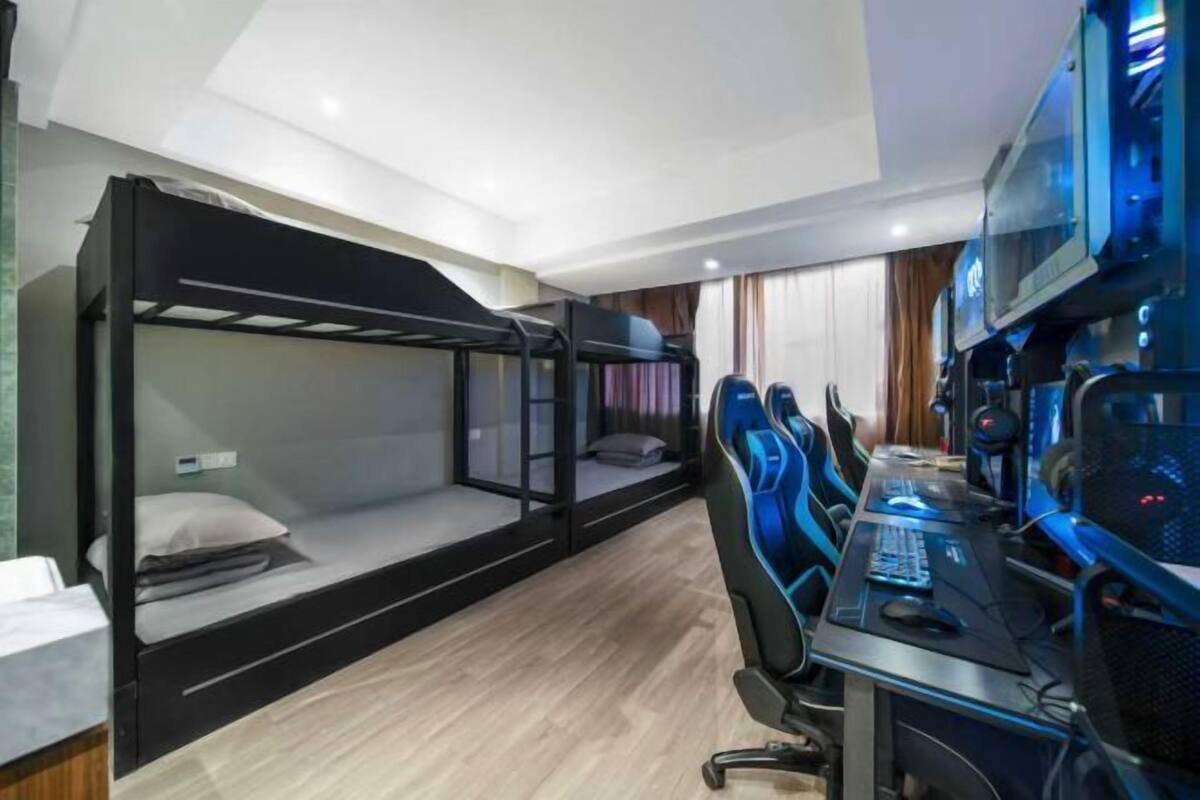 Ein Zimmer mit Etagenbetten, einem Schreibtisch mit Computer und Gaming-Stühlen.