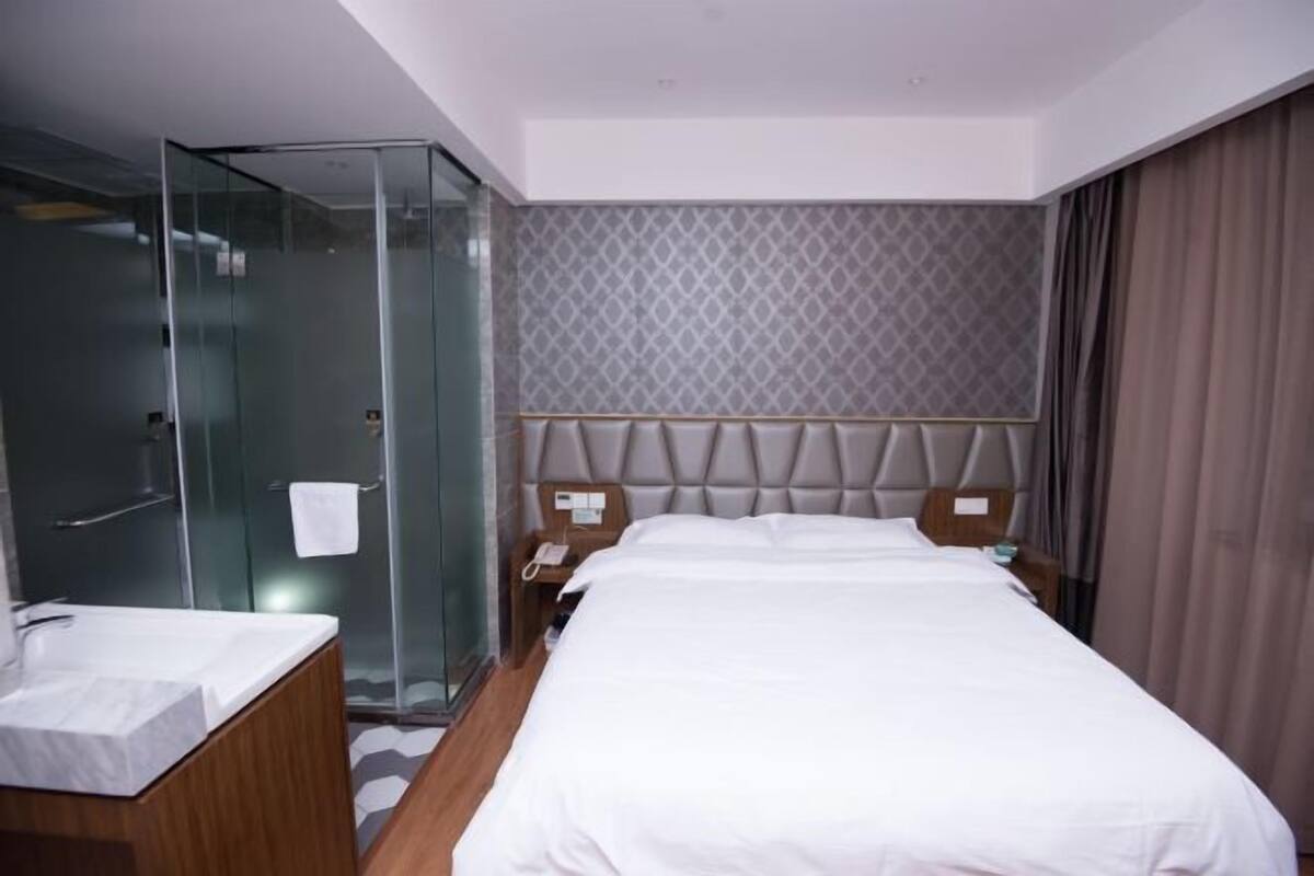 Ein Hotelzimmer mit einem großen Bett, einer Duschkabine aus Glas und einem Holzanrichte mit Waschbecken.