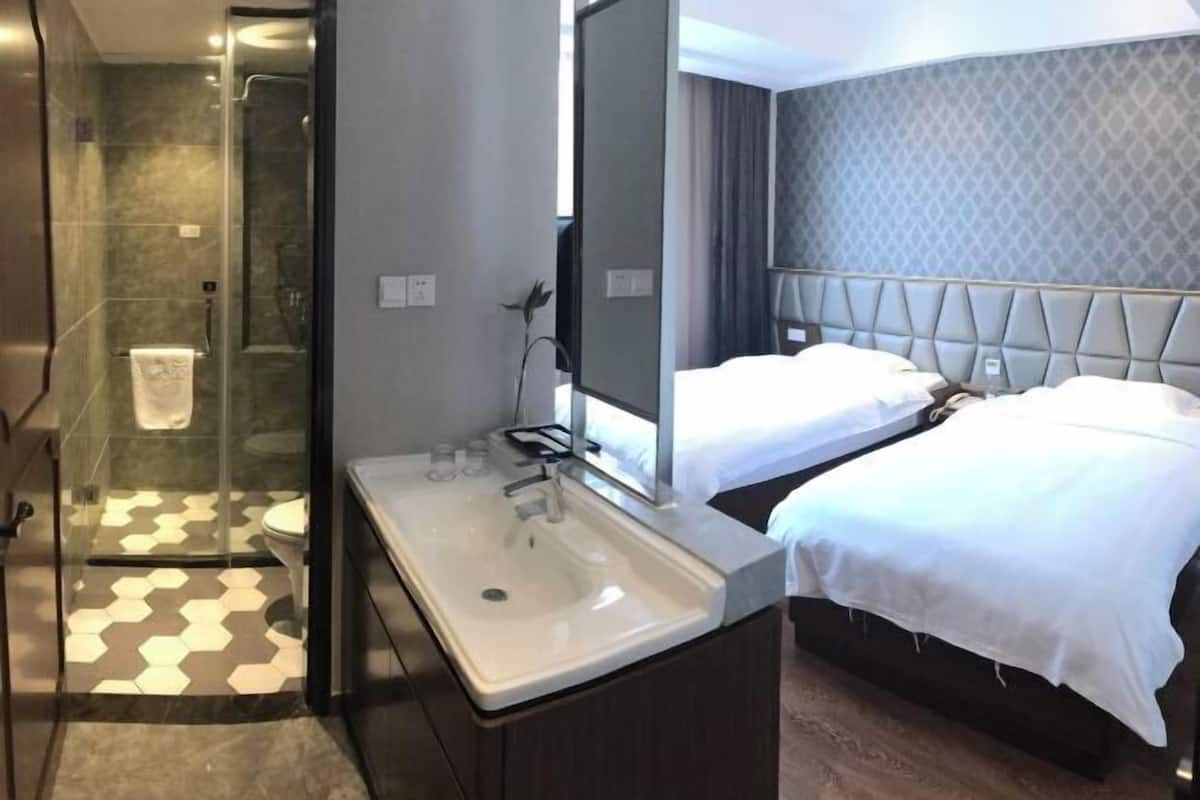 A hotel room with a modern design, including a large mirror, a double bed, a separate shower area, and a bathroom with a large sink.