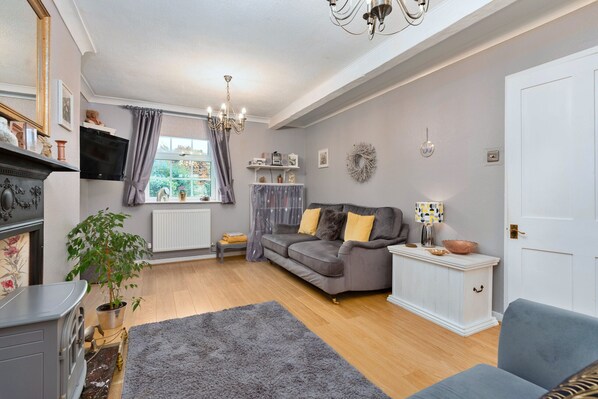 A cozy living room with a grey sofa, a blue armchair, a white cabinet, and a fireplace.