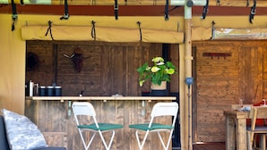 A wooden deck with a bar area, two folding chairs, a sofa, and a dining table. - The Safari Lodge at Rusty Lane Farm (Seend)