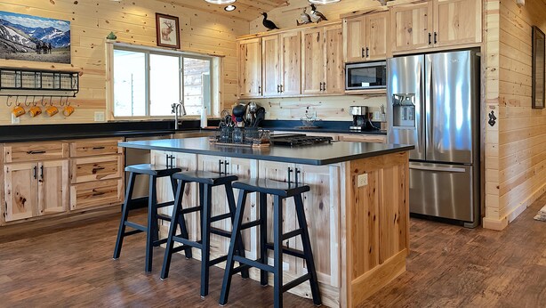Een moderne keuken met houten kastjes, een roestvrijstalen koelkast en een centraal keukenblok met barstoelen.