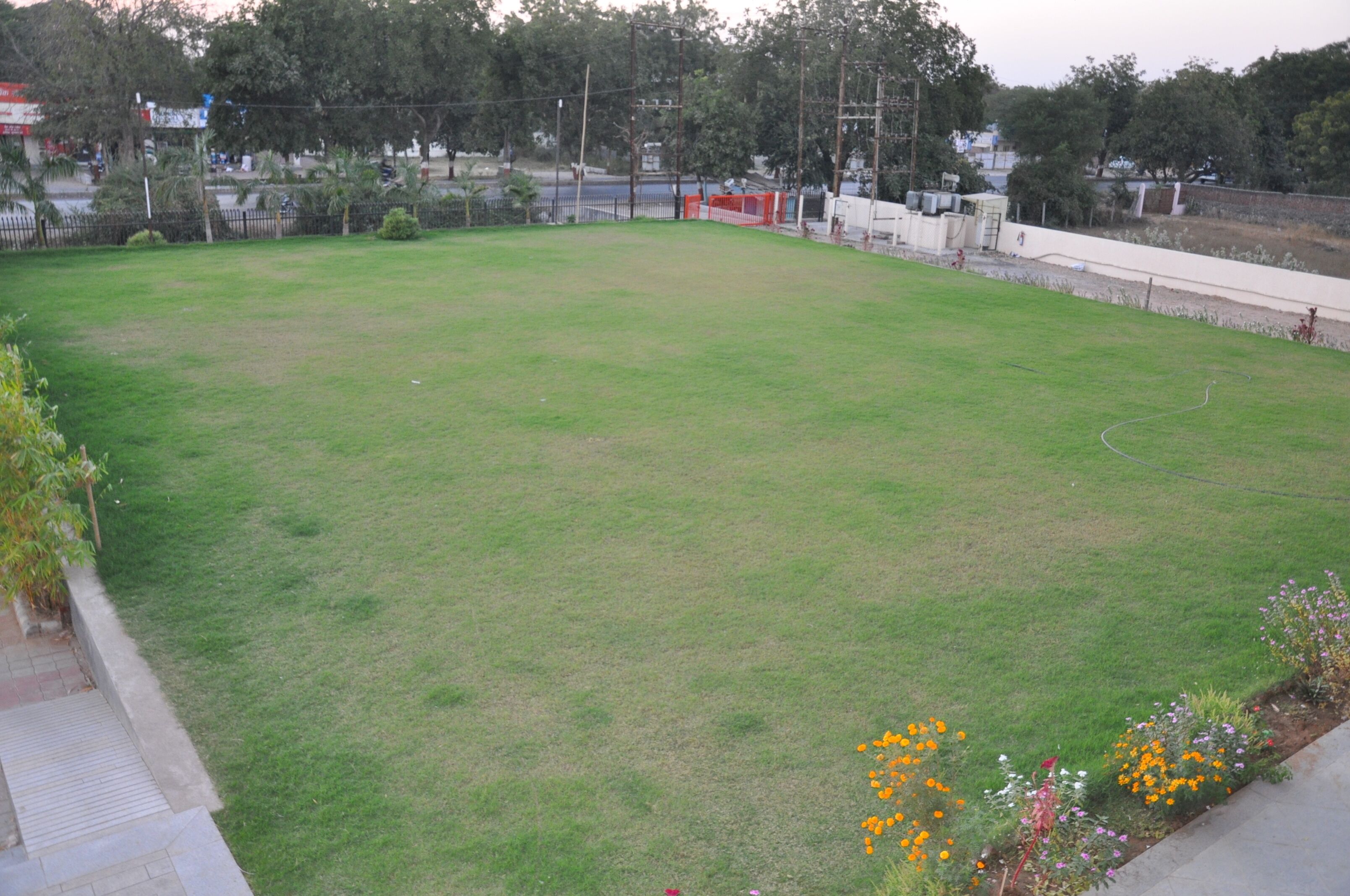 A large, open grassy area with a paved walkway on one side.