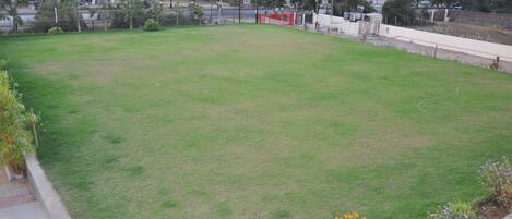 A large, open grassy area with a paved walkway on one side.