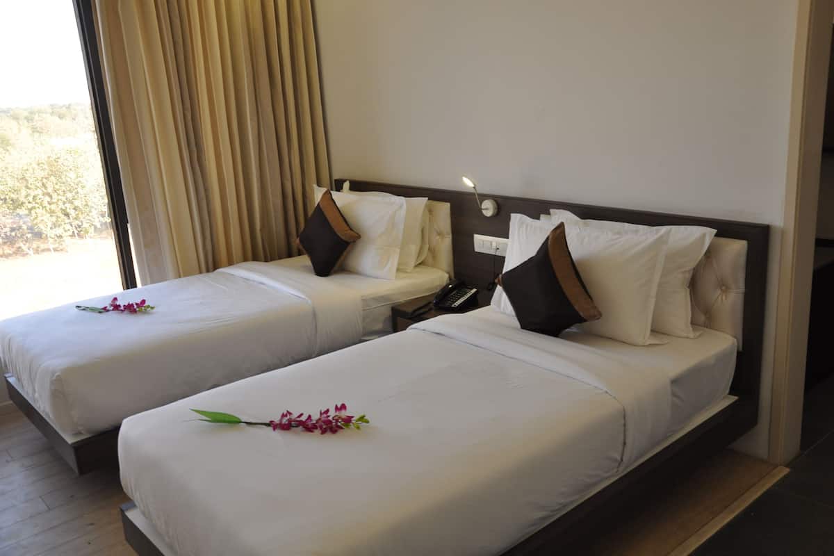 A hotel room with two beds, each with white linens and decorative pillows.