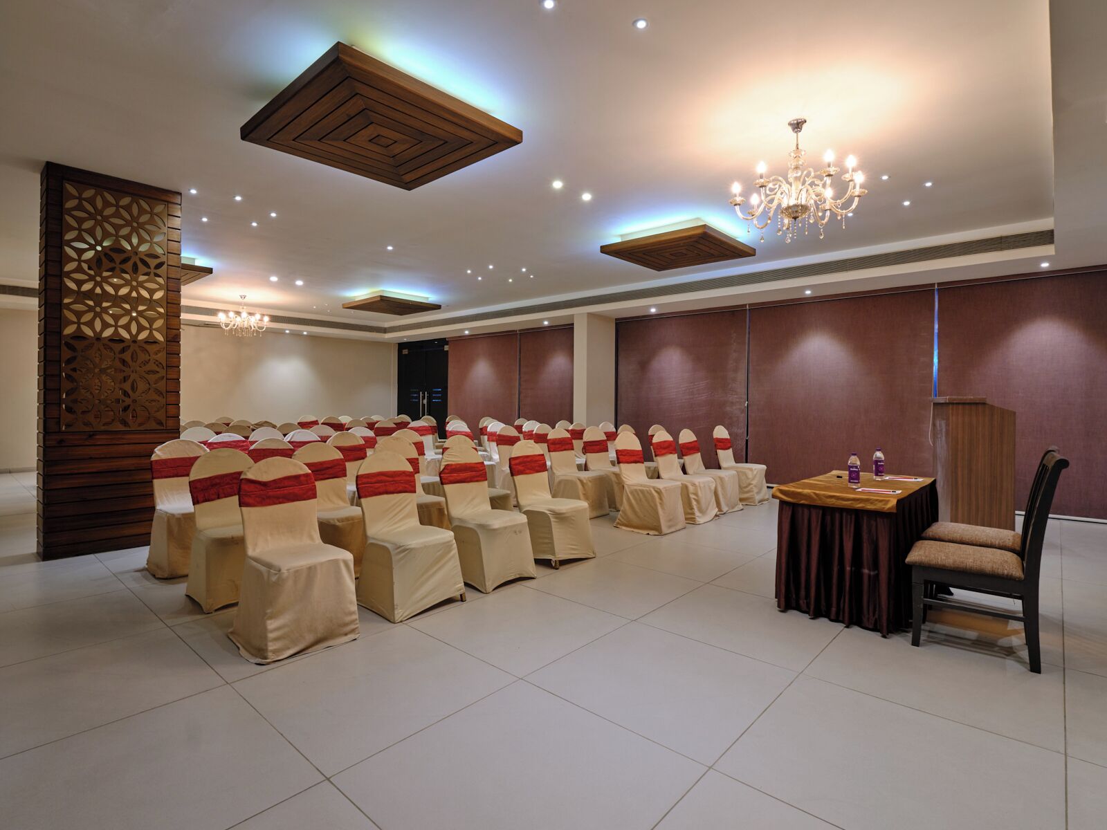 A conference room with rows of chairs, a table, and a chandelier.