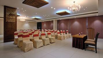 A conference room with rows of chairs, a table, and a chandelier.
