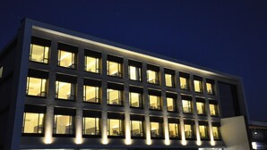 A modern building with multiple illuminated windows and a flat facade. - Pride Biznotel Manjusar (Savli)