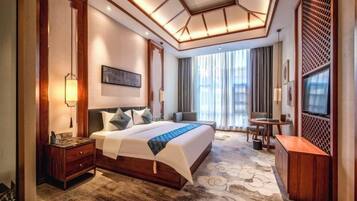 A hotel room with a large bed, a desk, a TV, and a view of the outdoors.