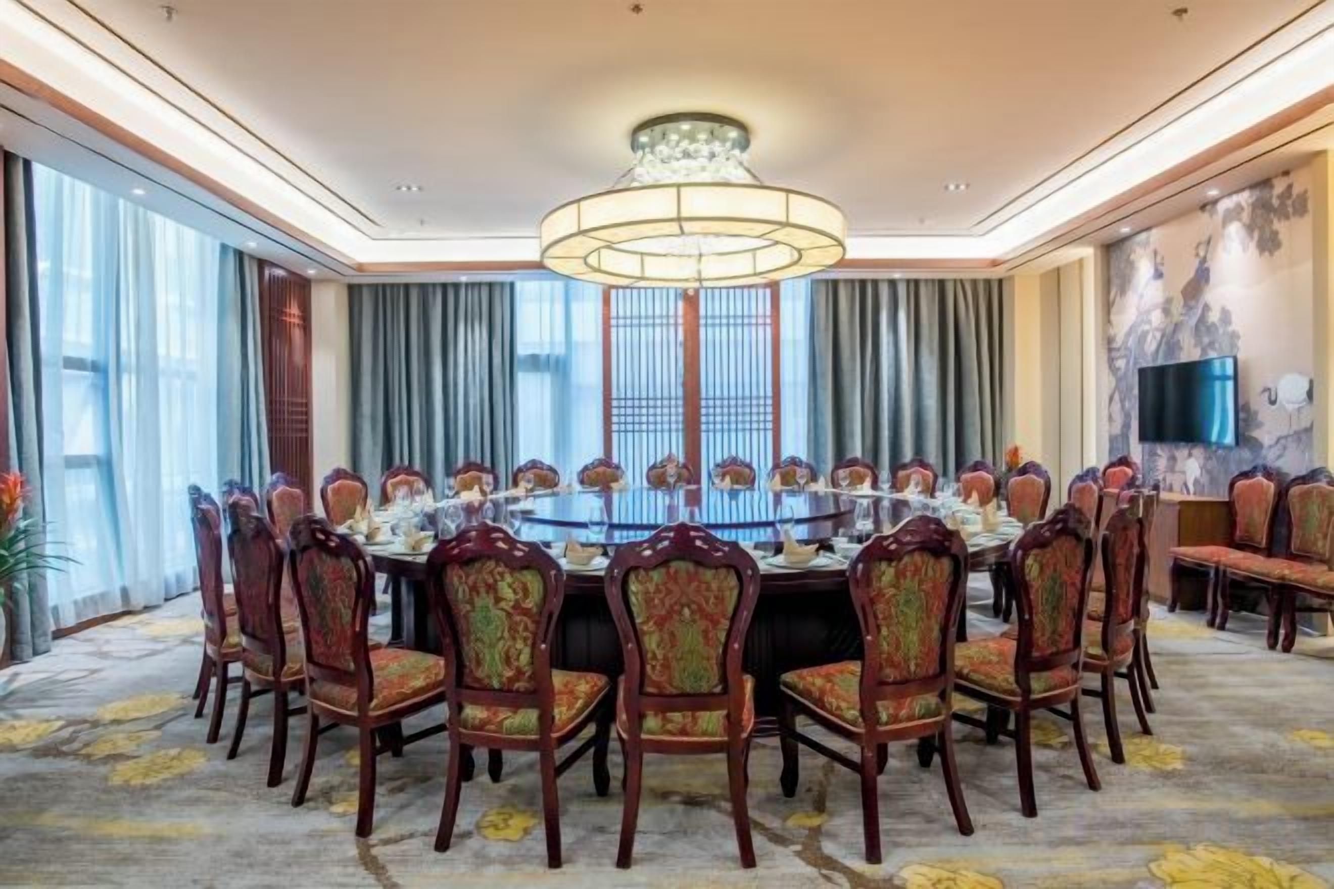 A conference room with a round table, chairs, and a chandelier.
