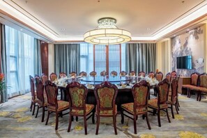 Un salón de conferencias con una mesa redonda, sillas y una araña.