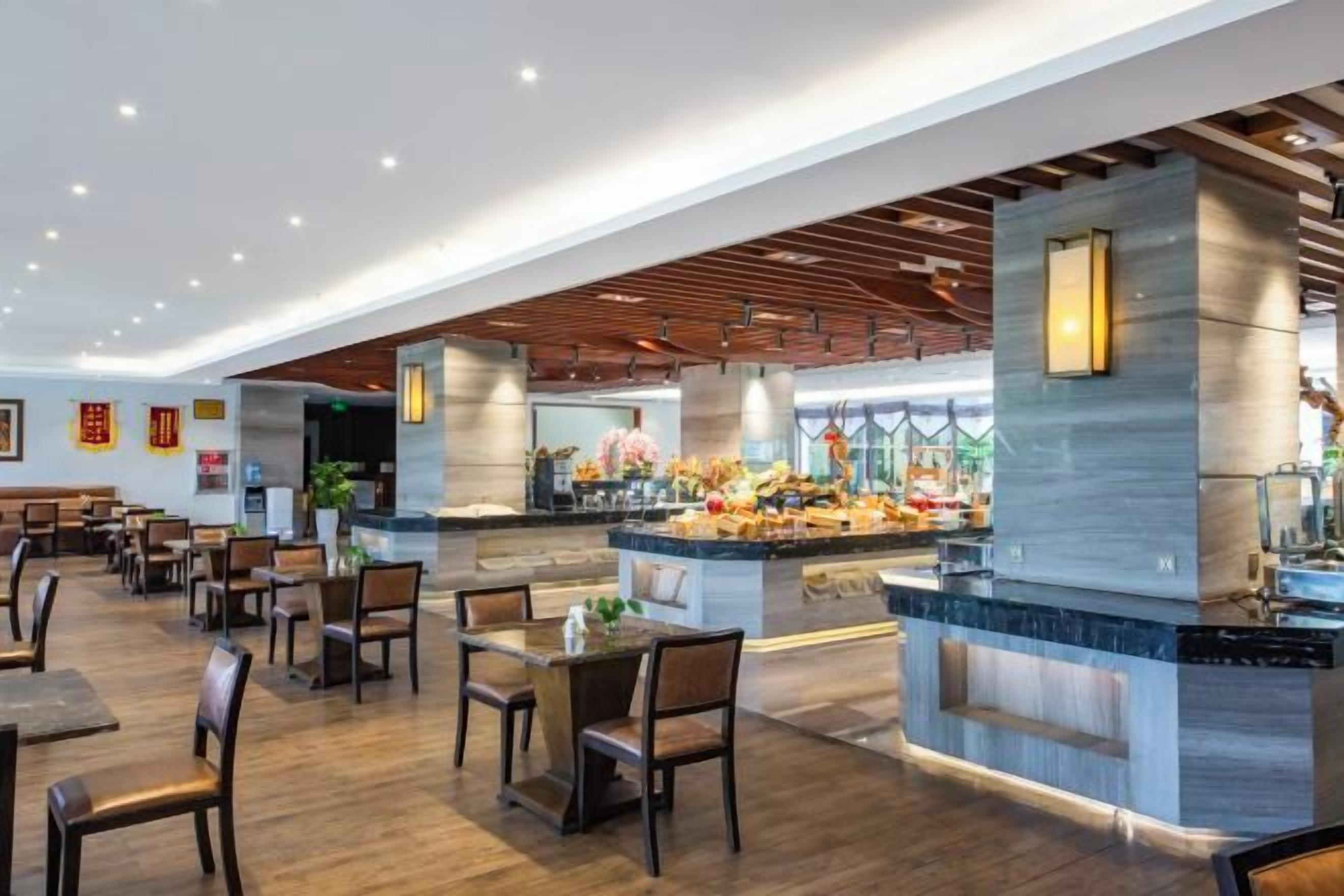 Un restaurante espacioso con una isla central, varias zonas de estar y un diseño de interiores moderno.