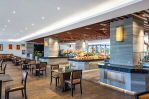En rummelig restaurant med en central ø, flere siddeområder og et moderne interiørdesign.