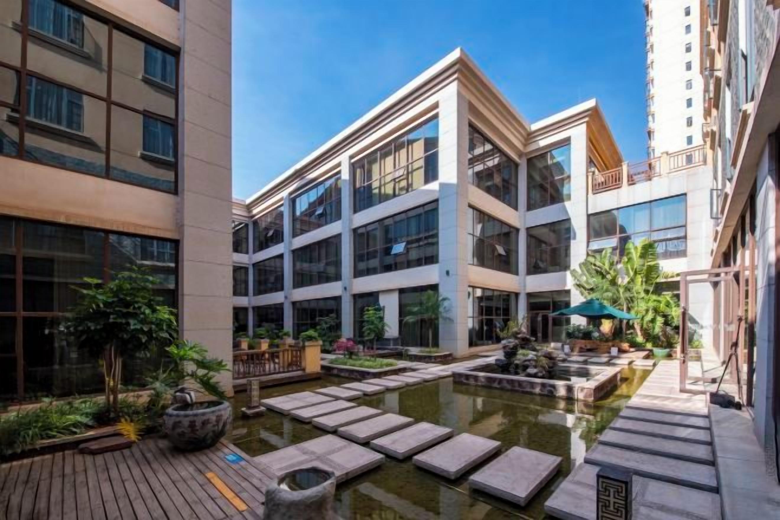 A courtyard with a water feature, potted plants, and a wooden deck.