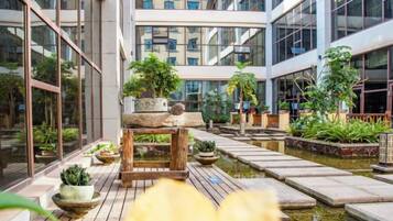 Un bâtiment moderne doté d’une cour intérieure agrémentée de plantes en pot et d’un petit élément décoratif aquatique.