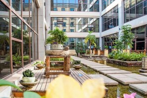 Un edificio moderno con un patio central que incluye plantas en macetas y una pequeña fuente.