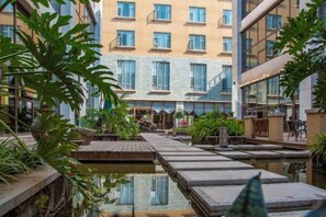 A hotel courtyard with a central water feature, wooden walkways, and surrounding greenery. - Yuanmou Grand Hotel (Yuanmou)