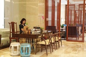 A dining area with a wooden table, chairs, and a decorative screen. - Yuanmou Grand Hotel (Yuanmou)