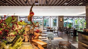 Un restaurante moderno con una escultura de madera central, mesas y sillas para comer.